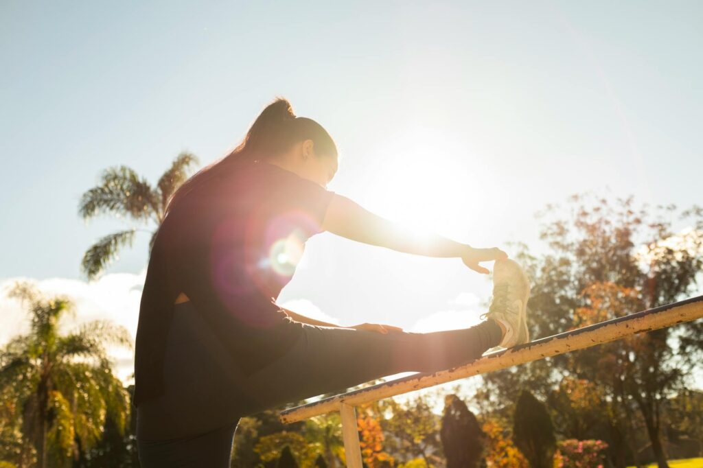 A person stretching outdoors at sunrise in a quiet park, soft warm light