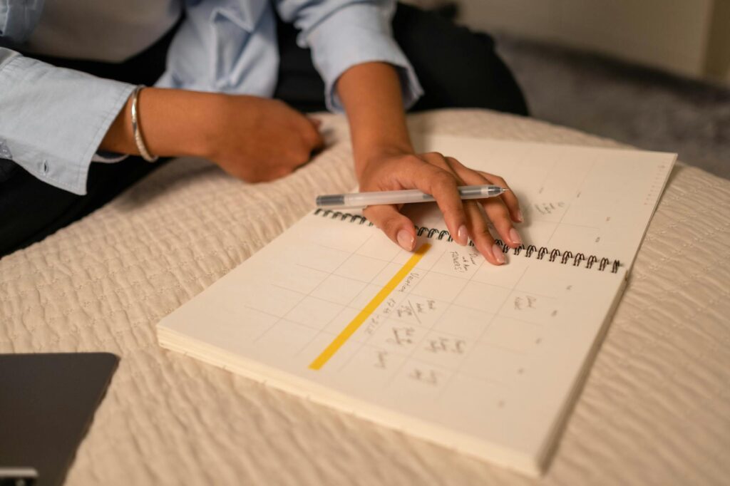 A person planning in a notebook on a calm wooden desk in soft warm light